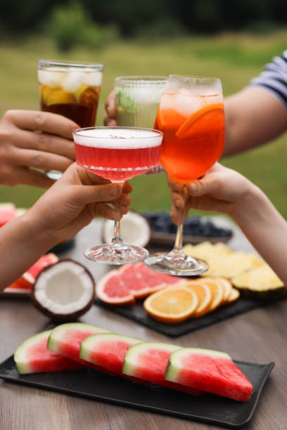 istock Friends clinking glasses with cocktails at table outdoors, closeup 1908793574