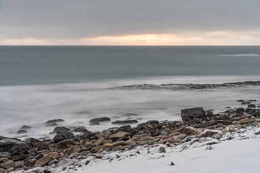 Rocky shores of Varanger Peninsula during the Polar Nigh. Waves crashing on the shore, long exposure. Ekkerøya, Northern Norway