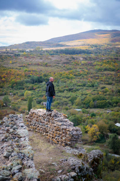 Solitary Moment: Man Standing on Mountain Fortress Ruins, Taking in the Scenery