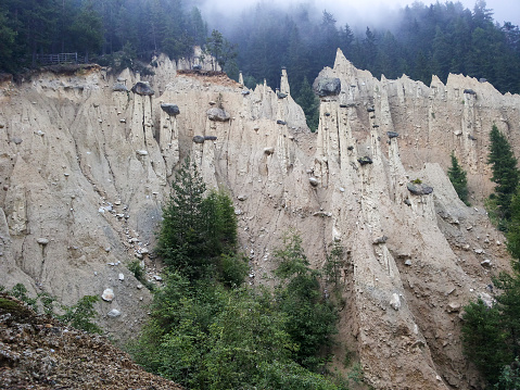 Surreal shapes of the famous Piramidi di terra (Earth Pyramids) rock formations eroded by wind in fog, Puster Valley, South Tyrol, Italy