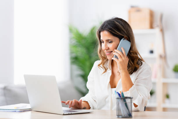 istock Freelance woman working from home using phone and laptop 1908854742