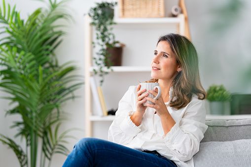 Portrait with focus on a mature casual woman enjoying morning coffee at home