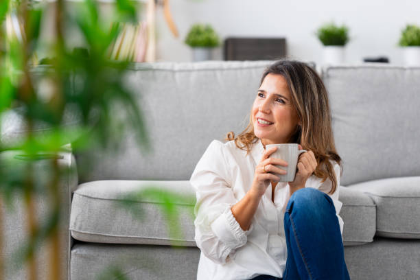 istock Woman drinking coffee sitting on the floor at home 1908856319