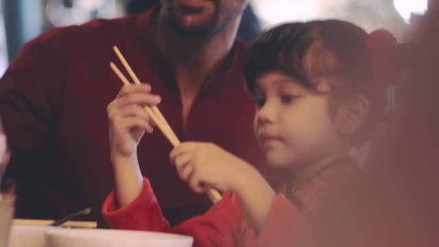 Father and daughter eat noodles together