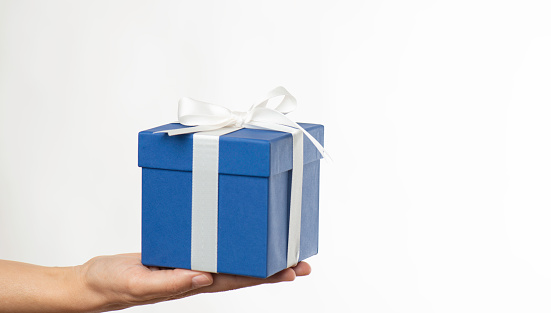 Woman giving blue gift box against white background.