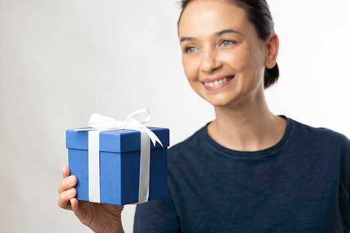 Smiling woman holding a blue gift box, white background.