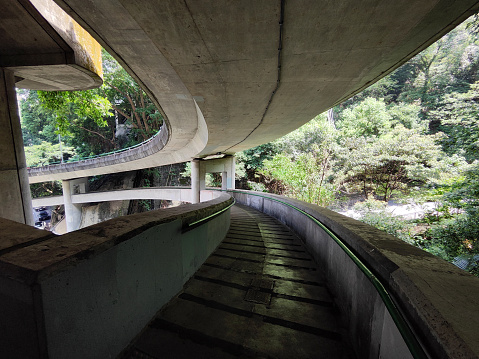 Footbridge under an elevated road over a green bush in Hong Kong central district, Hong Kong island.