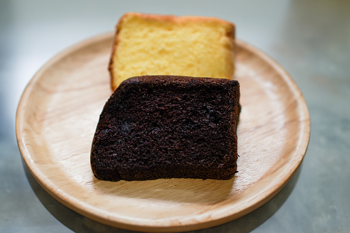 View of ready-to-eat dark chocolate and butter cake slices on a wooden dinner plate