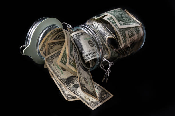 istock Clear glass jar with 1 US dollar bills on a  black background 1908907799