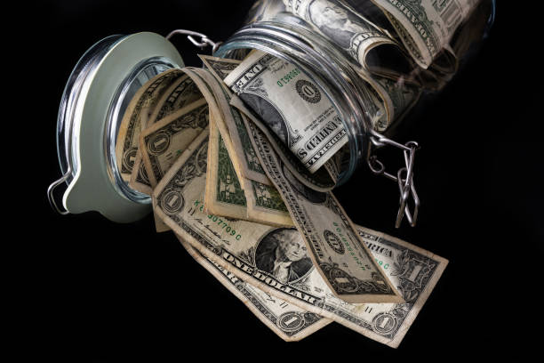 istock Clear glass jar with 1 US dollar bills on a  black background 1908907806