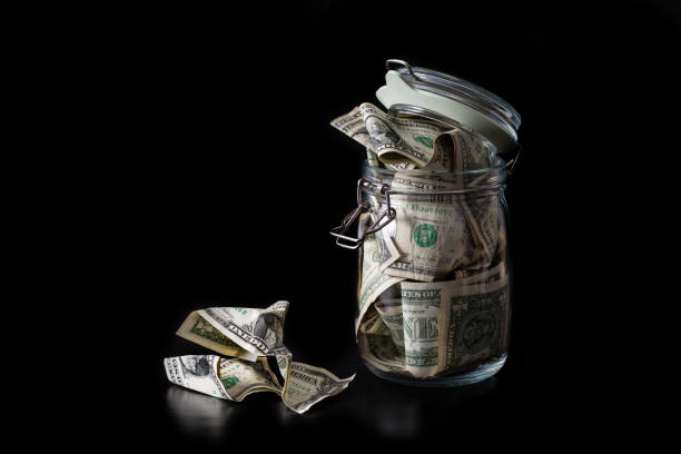 istock Clear glass jar with 1 US dollar bills on a  black background 1908907808