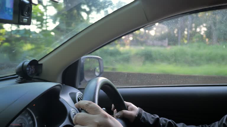 The man driving a car on the rural road. Close-up shot.