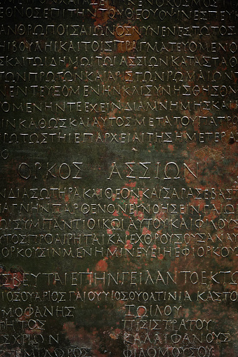 An inscription in Latin or Greek minted on a sheet of metal. Decorative elements of ancient Mediterranean architecture. Vertical image.