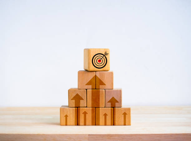 istock Target icon on top of wooden cube blocks stack as pyramid shape with rise up arrows on white background. Business goal process, Growth marketing, profit, investment, economic improvement concepts. 1908961110