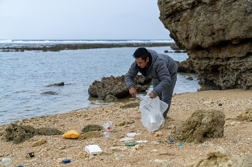 Mid adult male cleaning up various plastic waste on a beach in Japan
