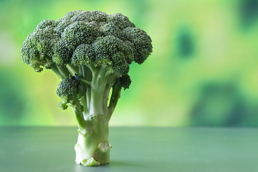 Stock photo showing close-up view of tree-like stem of broccoli against a mottled green background.