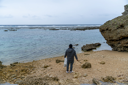 Mid adult male cleaning up various plastic waste on a beach in Japan