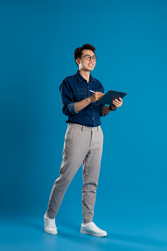 Portrait of young Asian business man posing on blue background