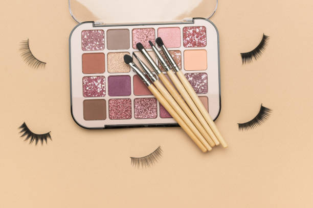 istock Scattered false eyelashes and an open set of eye shadow on a beige background. 1909034777