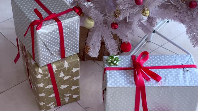 Christmas gifts in boxes of blue and pink lie next the decorated Christmas tree at home 4k stock video
