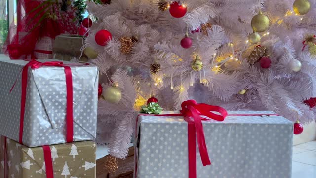 Christmas gifts in boxes of blue and pink lie next the decorated Christmas tree at home 4k stock video