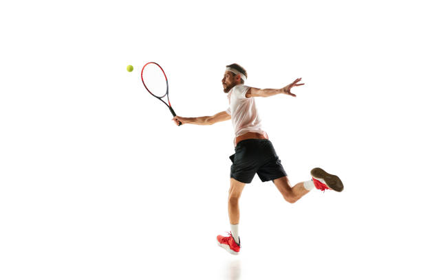istock Competitive man, tennis player during game in motion, hitting ball with racket, playing isolated over white background. Sport 1909046580