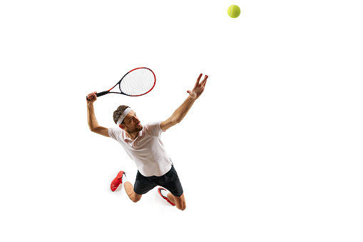 Top view. Dynamic image of sportsman, tennis player in motion, serving ball with racket, playing isolated over white background. Concept of sport, hobby, active and healthy lifestyle, competition