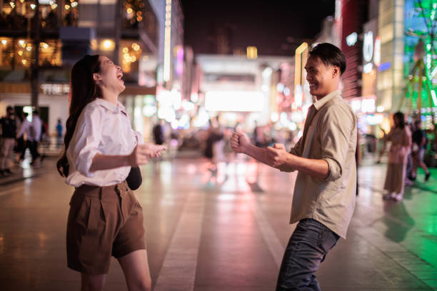 Smiling friends are having fun while walking in the city at night.