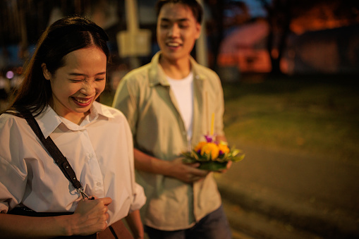 Smiling couple is walking with krathong in hands, on night of the Loy Krathong festival.