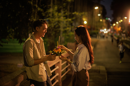 A smiling couple admires their chosen krathong on a festive Loy Krathong night.