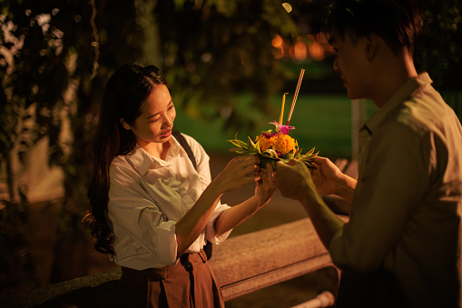 A smiling couple admires their chosen krathong on a festive Loy Krathong night.