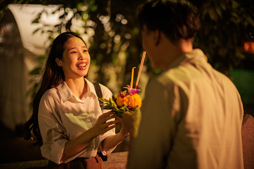 A smiling couple admires their chosen krathong on a festive Loy Krathong night.