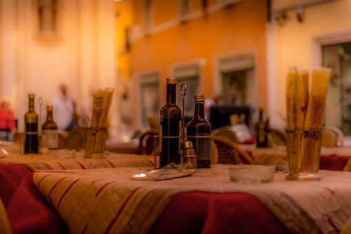 ltable of a restaurant with vinegar and olive oil at old town of Riva del Garda in Italy. The background is blurred.