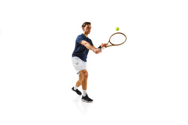 istock Young athletic man, tennis player in motion, hitting ball with racket isolated over white background. Dynamic game 1909094965