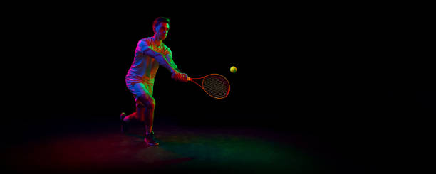 istock Competitive man, tennis athlete in motion during game, playing, practicing against dark background in neon light 1909095490