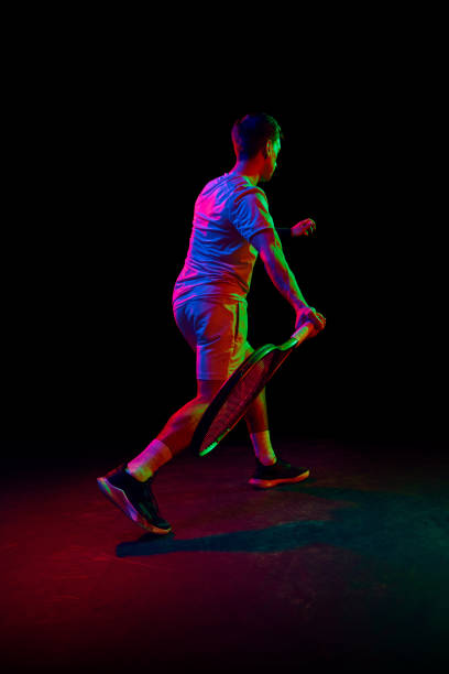 istock Young man, tennis player during game, playing, practicing against dark background in neon light 1909095506