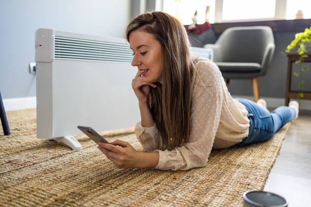 istock Young woman sitting in front of a radiator 1909148371