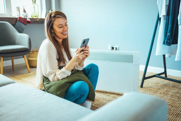 istock Woman and radiator using smartphone app for temperature control 1909150014