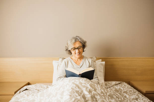 istock Senior woman reading a book on bed. 1909152164