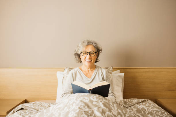 istock Senior woman reading a book on bed. 1909152702
