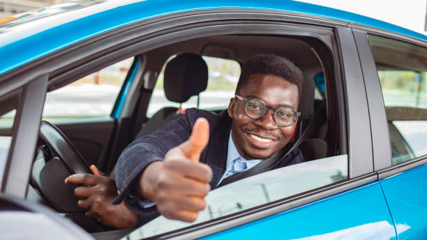 istock Happy african man show thumbs up inside car. 1909162314