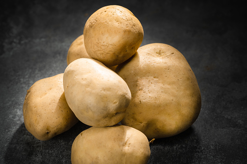 fresh potatoes on a black stone background