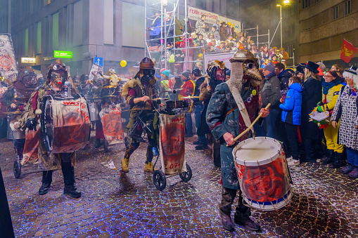 Lucerne, Switzerland - February 21, 2023: Band of musicians in costumes march in the streets, part of the final night parade of the Fasnacht Carnival, in Lucerne (Luzern), Switzerland