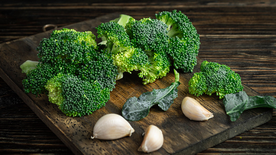 Fresh green broccoli cut on a cutting board on the background of an old wooden board.