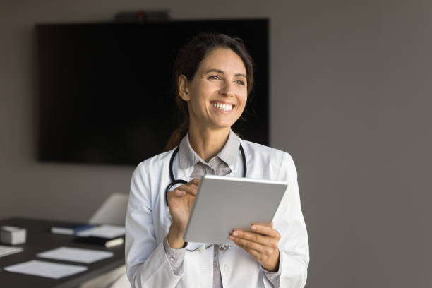 istock Positive adult doctor woman using tablet computer in office 1909333379