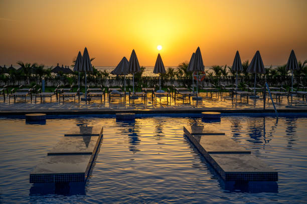 Sunset above a swimming pool of the luxury hotel Riu Baobab, Senegal, Africa Ponto, Senegal - March 02, 2023 : Sunset above a swimming pool of the luxury hotel Riu Baobab, a five star hotel in Senegal, West Africa. senegal beach stock pictures, royalty-free photos & images
