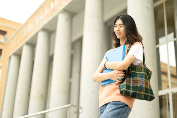 istock young oriental lgbti university student leaving the university with a folder in his hand going down stairs 1909358401