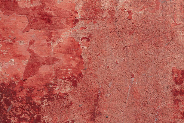 Red concrete wall with deep scratches and chips. Various variations of abrasions.