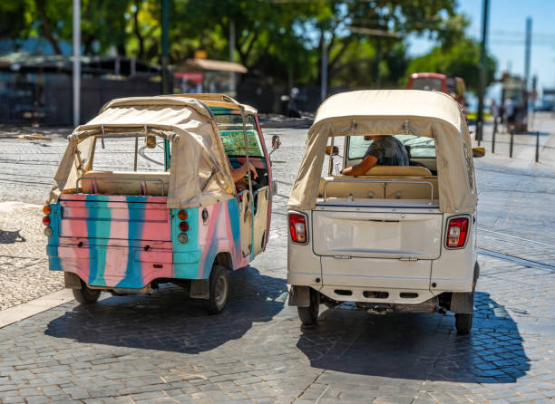 Two Piaggio Ape Calessino 200 three-wheeled tourist Tuk tuks parked on a cobblestone street in Lisbon in Portugal with tram tracks on the ground. Two Piaggio Ape Calessino 200 three-wheeled tourist Tuk tuks parked on a cobblestone street in Lisbon in Portugal with tram tracks on the ground. no rickshaws sign stock pictures, royalty-free photos & images