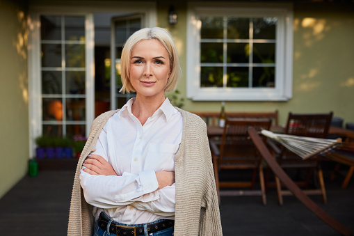 Portrait of mature woman standing outside her home backyard patio